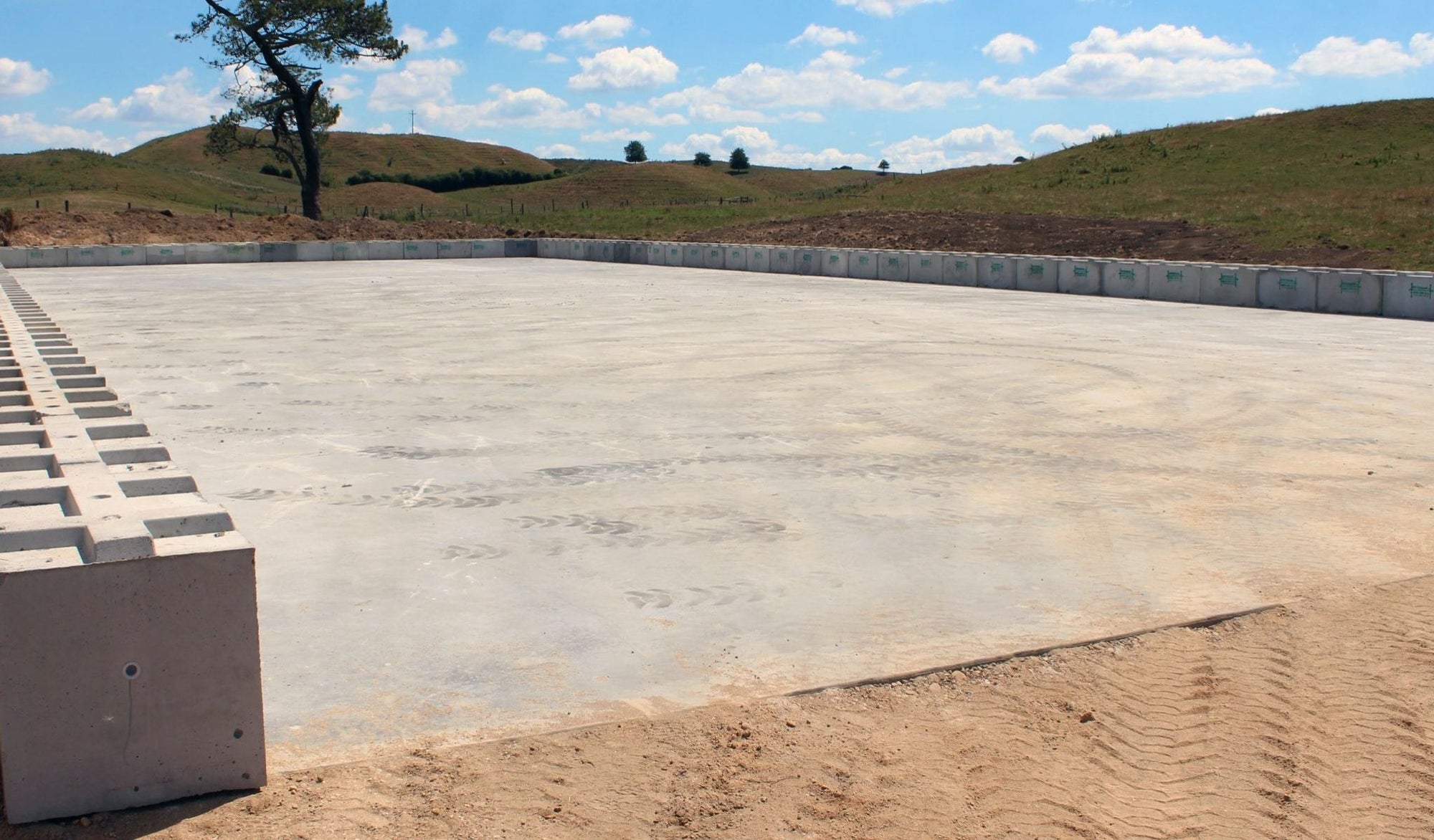Base row of Interbloc concrete blocks placed on a concrete pad of a silage bunker