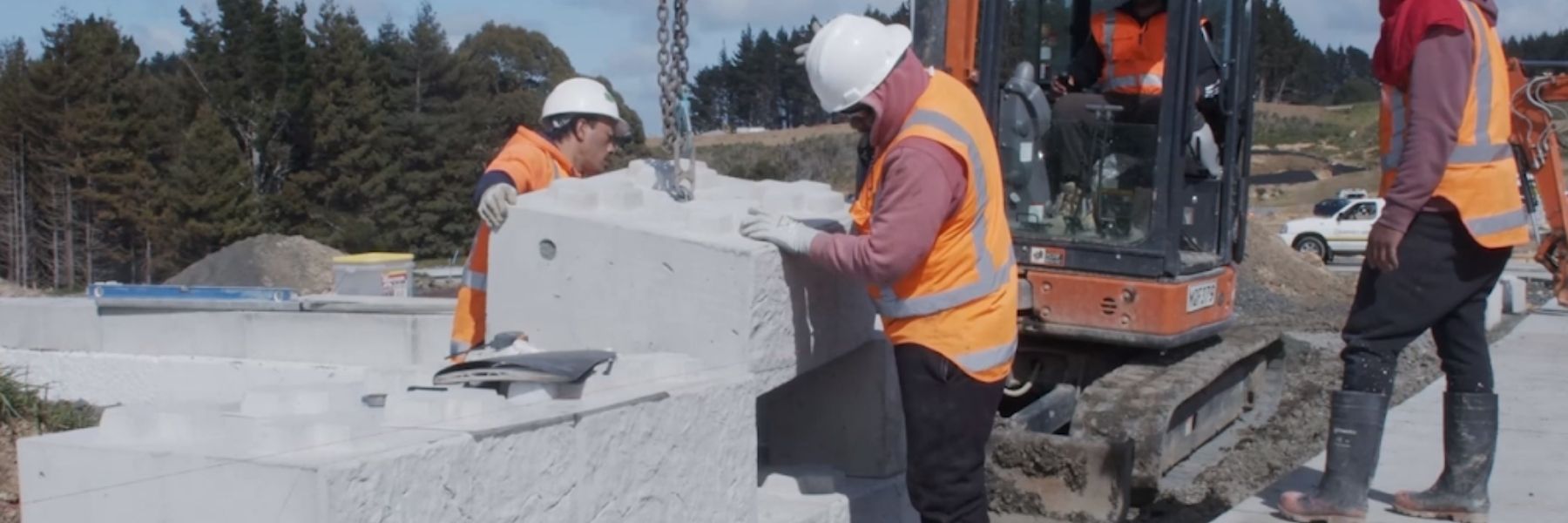 2 men installing a 800 Stonebloc base concrete block  onto a 1200 Stonebloc base concrete block