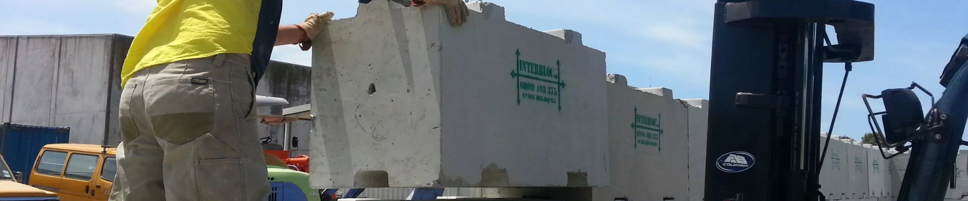Worker installing a standard 1200 Interbloc concrete block on top of the already-built 2 rows underneath.