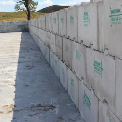 Close up shot of a silage bunker wall made from Interbloc mass concrete blocks with a tree in the background