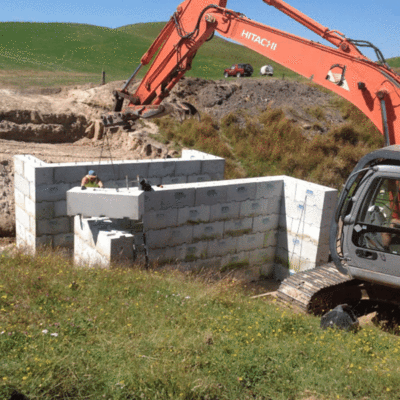 1800 standard Interbloc concrete block bein placed on the top layer of a culvert by a digger