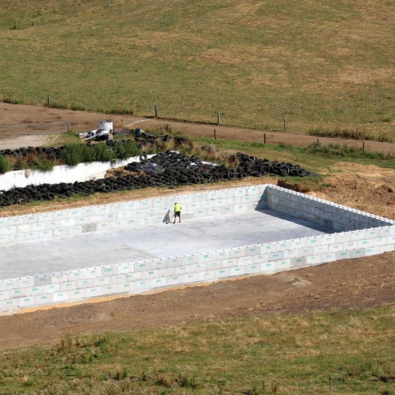 Man sweeping concrete foundation of an Interbloc concrete block silage bunker