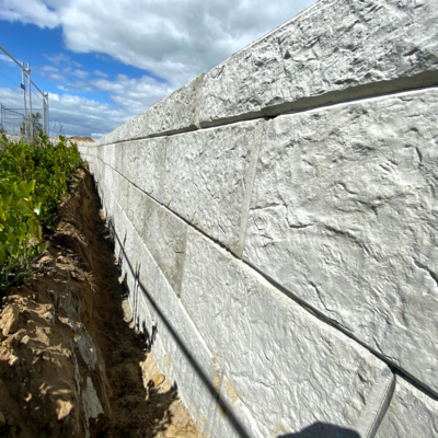 Profile view of a textured Stoenbloc retaining wall next to a planted garden 