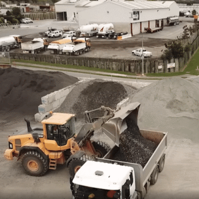 Yellow digger getting aggregate from Interbloc bins and dumping it into a truck